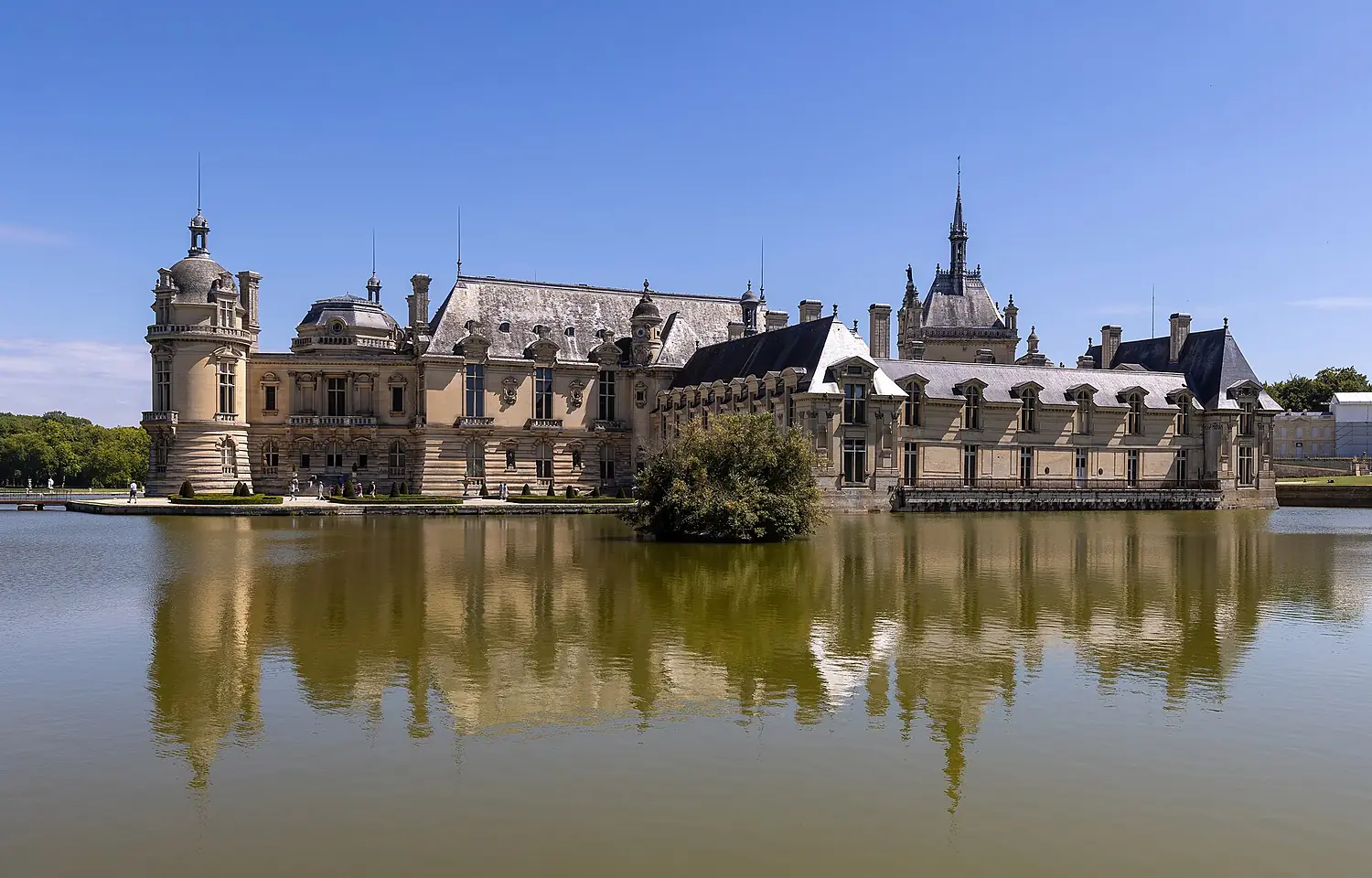 Side view of the Château de Chantilly with water reflection and blue sky Oise France